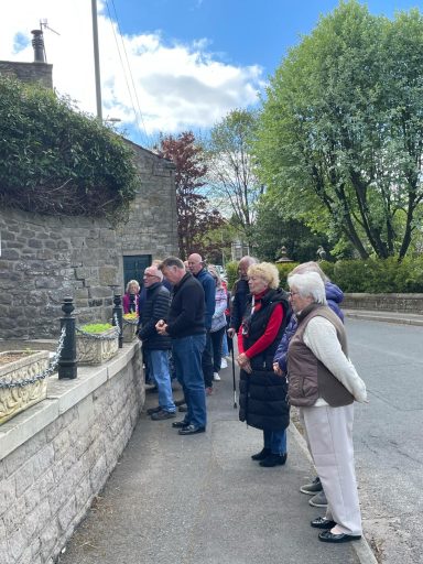 A group of people observing a scene by a stone wall on a pleasant day.